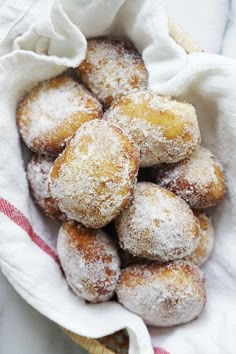 a basket filled with powdered sugar covered donuts