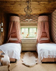 two twin beds in a room with pink curtains and rugs on the floor next to each other