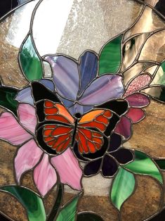 a colorful stained glass butterfly sitting on top of a wooden table next to a mirror