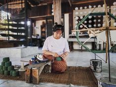 a woman sitting on top of a rug next to a pile of green balls and yarn