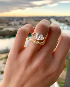 a woman's hand holding an engagement ring with a diamond in the middle and two gold bands around it