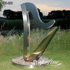 a large metal harp sitting on top of a lush green field