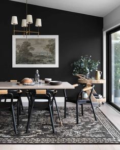 a dining room with black walls and wooden table in the foreground is an image of a landscape