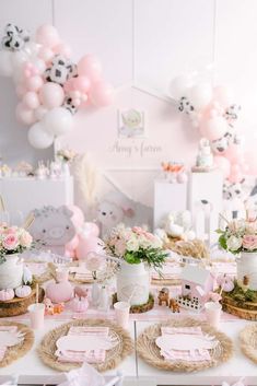 a table set up for a baby shower with pink and white balloons in the background