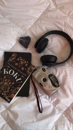 a camera, headphones, and book on a bed