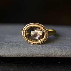 a close up of a ring on top of a piece of stone with a black diamond in the center