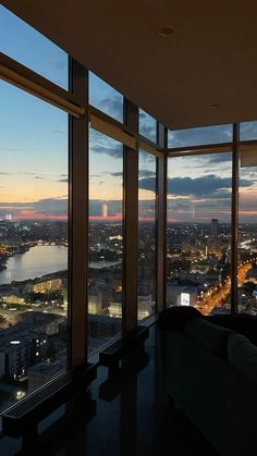 a living room filled with furniture and large windows overlooking the city at sunset or dawn