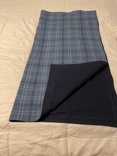 a bed with a blue and white blanket on top of it next to a pillow