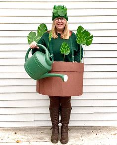 a woman in green is holding a watering can and potted plant with leaves on it