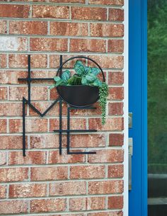 a brick wall with a black metal planter on it and a blue door in the background