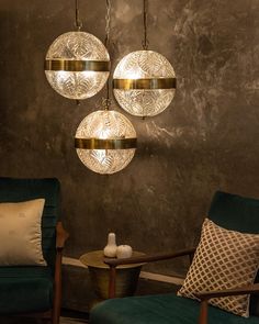 three circular lights hanging from the ceiling in a living room with green chairs and pillows