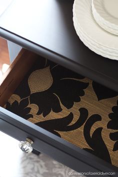 a close up of a drawer on a table with plates and napkins in it