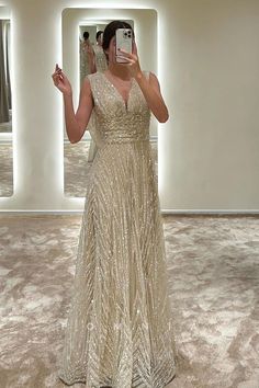 a woman taking a selfie in front of a mirror wearing a gold sequin gown