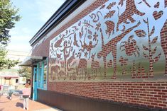 people walking past a brick building with graffiti on it