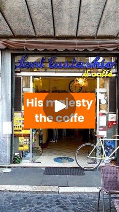 a bicycle parked in front of a coffee shop with an orange sign that reads, his majesty the coffee