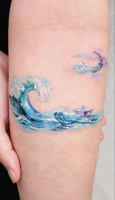 a woman's arm with an ocean wave tattoo on it