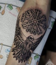 a black and white tattoo with a bird on it's arm, in the middle of