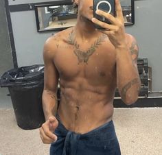 a shirtless man taking a selfie in front of a mirror with his cell phone