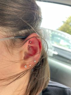 a woman with glasses and red nose piercings on her ear in the back seat of a car