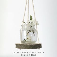 a glass jar hanging from a rope with flowers in it and the words little wood slice shelf 35x10cm