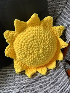 a crocheted yellow sunflower sitting on top of a gray and white blanket