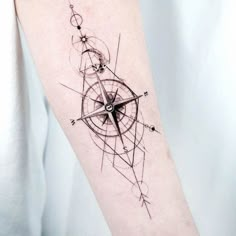 a person with a tattoo on their arm that has an arrow and compass in it