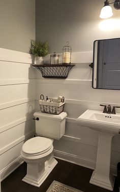 a white toilet sitting next to a sink in a bathroom on top of a hard wood floor