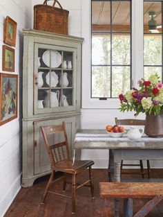 a dining room table and chairs with vases on top of them, next to an old china cabinet