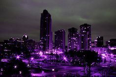 the city is lit up at night with purple lights