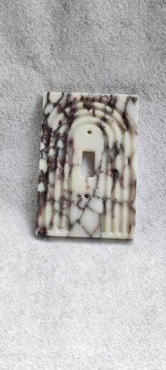 a marble light switch cover on a gray surface with white and brown swirls in the middle