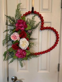 a heart shaped wreath with flowers hanging on the front door to welcome someone who is in love