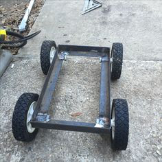 a metal cart sitting on top of a sidewalk next to a cement floor with two wheels