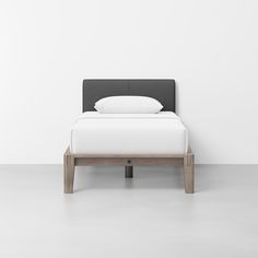 a bed with a white pillow on top of it next to a wooden foot board