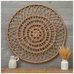 a wicker wall decoration with vases on a shelf next to it and a wooden paneled wall in the background