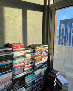 a stack of books sitting on top of a window sill next to a building