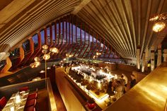 the inside of a restaurant with people eating at tables and lights hanging from the ceiling