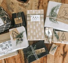 christmas wrappings are laid out on a wooden table with pine cones and evergreen branches