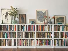 a bookshelf filled with lots of books on top of a hard wood floor