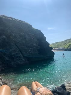 a woman laying on the beach with her feet in the water