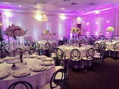 the tables are set up with white linens and purple lighting for an elegant wedding reception