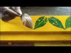 a person is holding a leaf over a yellow box with green leaves on it,