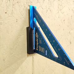 a blue triangle shaped ruler mounted to the side of a wall