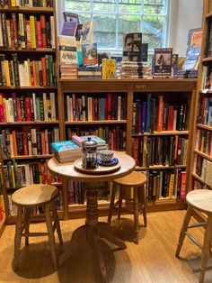 two wooden chairs sitting at a table in front of a book shelf filled with books