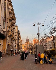 many people are walking down the street near buildings