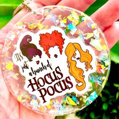 a hand holding a plastic keychain with stickers on it that says, i'm humbly hocus pocus