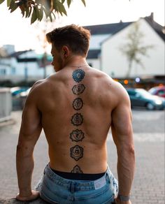 a man sitting on the ground with his back to the camera and tattoos on his back