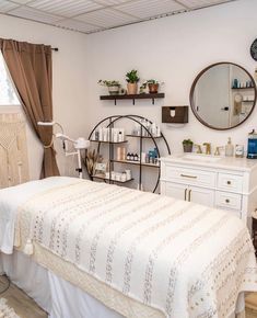 a white bed sitting under a mirror in a bedroom