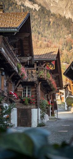 an old wooden building with flower boxes on the outside and mountains in the back ground