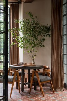 a table with chairs and a potted plant on top of it in front of a window