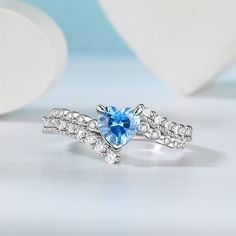 a heart shaped blue topazte ring on a white surface